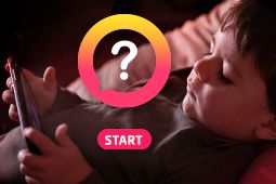 An alone toddler is looking at a smartphone in dark at night