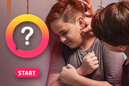 Two boys are bullying a boy in the school hallway and one of the bullies is recording the event with his smartphone  