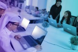Students sitting on a table where each student is using a laptop.