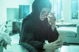 امرأة عربية تستخدم هاتفها المحمول بينما تفاجأ بشيء قرأته أو رأيته على هاتفها.