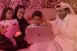 Family, a mother and her daughter, the father and his son, sitting together while using a laptop.