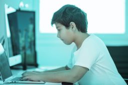 ولد يطبع على جهاز كمبيوتر المحمول.