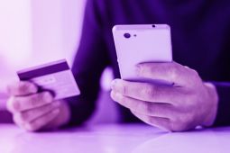 Hands of a man holding a smartphone and a credit card.