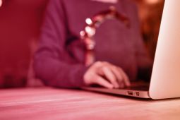 A hand of a young girl typing on the laptop.