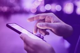 A person holding a smartphone, and scrolling with their finger.
