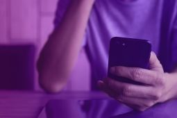 A hand of a young man holding a smartphone.