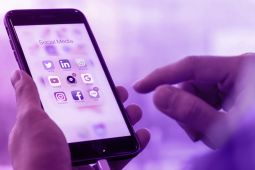 A hand of a person holding a phone, and the phone is showing all the social media applications on it.