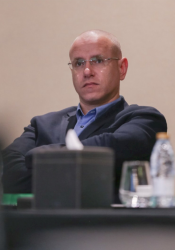 Omar Eldeeb is sitting on a chair with crossed arms.